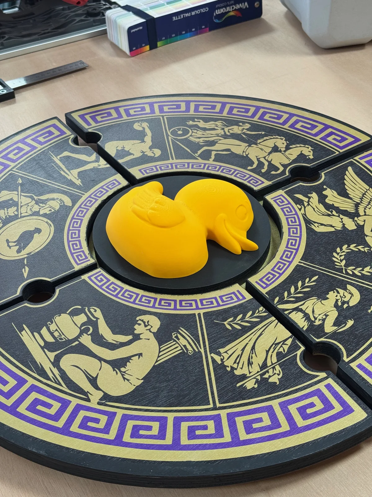 CNC-cut circular wooden panel with gold and purple Greek key motifs, UV printed